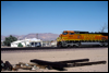 Dash 9-44CW 4511 rolls by Desert Market and railroad ties at Daggett, CA, 1999
