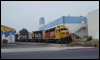 GP30 2750 and friends negotiate their way through the business park at Miramar, CA, in 1989.  The local is about to cross Distribution Avenue to spot RBL cars at a nearby industry. The building to the left with the colorful striping is Kid's Warehouse.